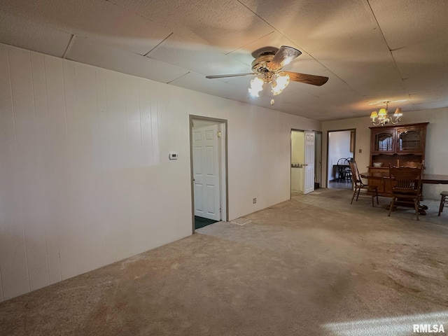 unfurnished room featuring a textured ceiling, ceiling fan with notable chandelier, and wood walls