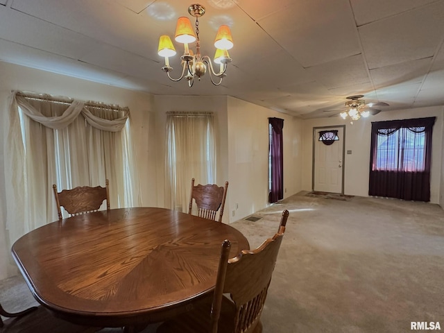 carpeted dining area with ceiling fan with notable chandelier