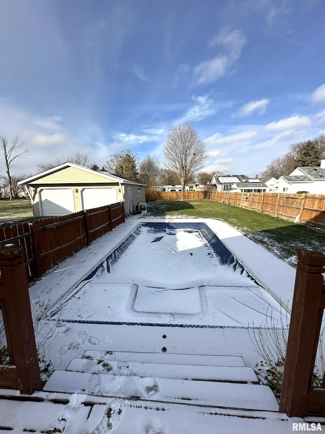 snow covered pool featuring an outbuilding, a yard, and a garage