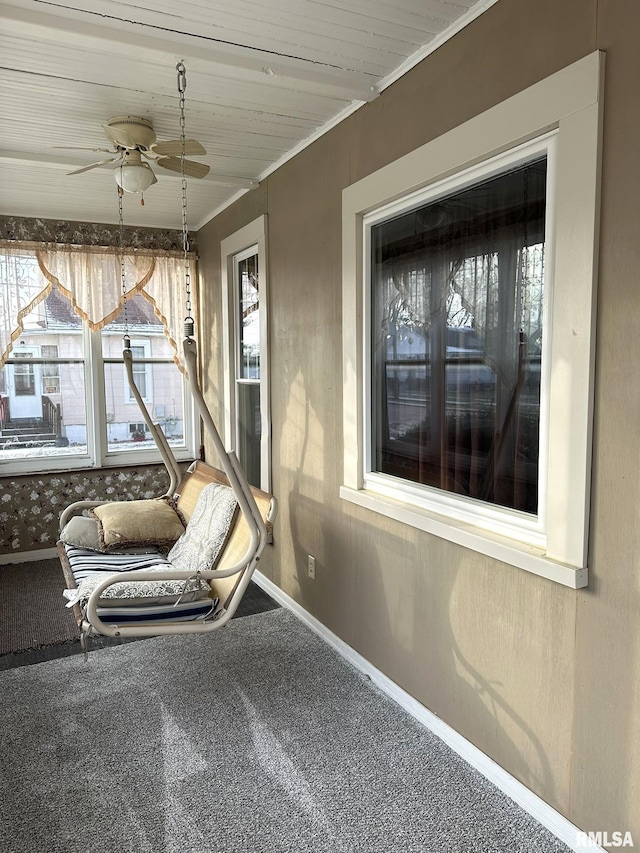 unfurnished sunroom featuring wood ceiling, ceiling fan, and a healthy amount of sunlight