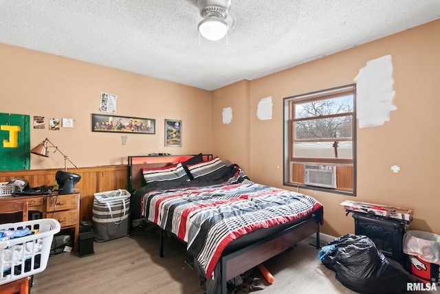 bedroom featuring cooling unit, a textured ceiling, and light wood-type flooring