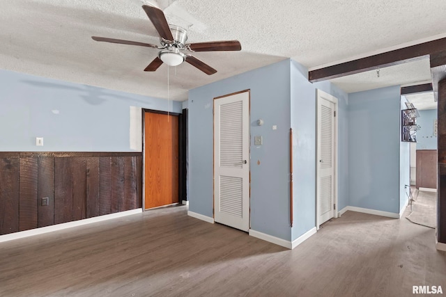 interior space with ceiling fan, beam ceiling, hardwood / wood-style floors, and a textured ceiling