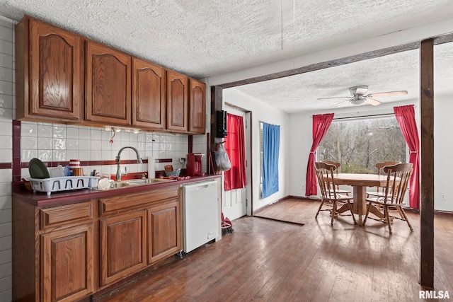 kitchen with sink, tasteful backsplash, white dishwasher, dark hardwood / wood-style flooring, and ceiling fan