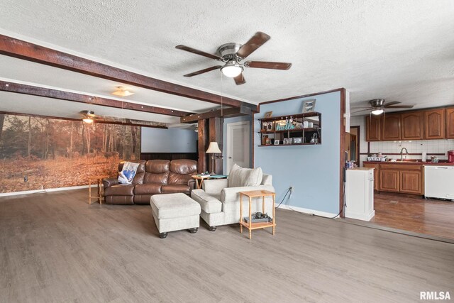 living room with sink, ceiling fan, beam ceiling, wood-type flooring, and a textured ceiling