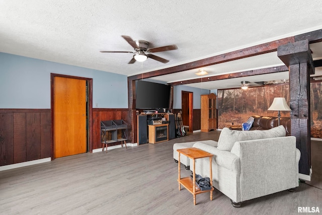 living room featuring hardwood / wood-style flooring, ceiling fan, and a textured ceiling