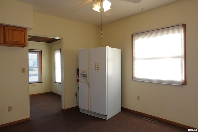 kitchen featuring a textured ceiling, ceiling fan, and white refrigerator with ice dispenser