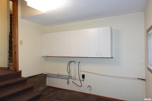 laundry room with cabinets and a textured ceiling