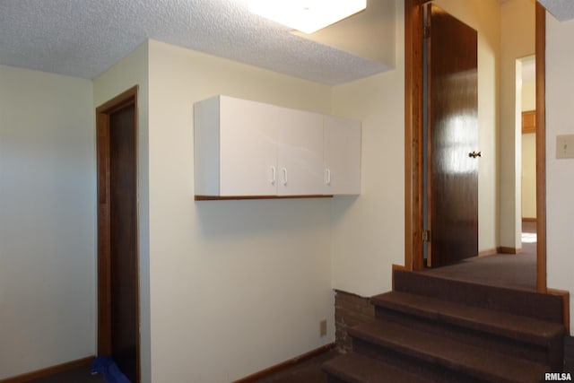 stairs featuring carpet and a textured ceiling