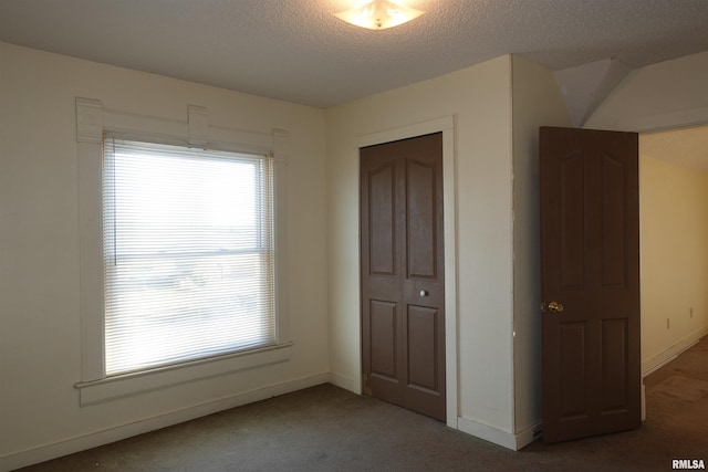 unfurnished bedroom featuring a closet, a textured ceiling, and dark colored carpet