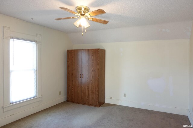 unfurnished room with carpet floors, a wealth of natural light, lofted ceiling, and ceiling fan