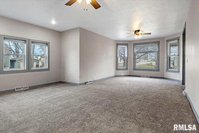 carpeted spare room featuring ceiling fan, a healthy amount of sunlight, and a textured ceiling