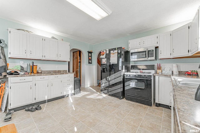 kitchen with light tile patterned flooring, sink, white cabinetry, and black appliances