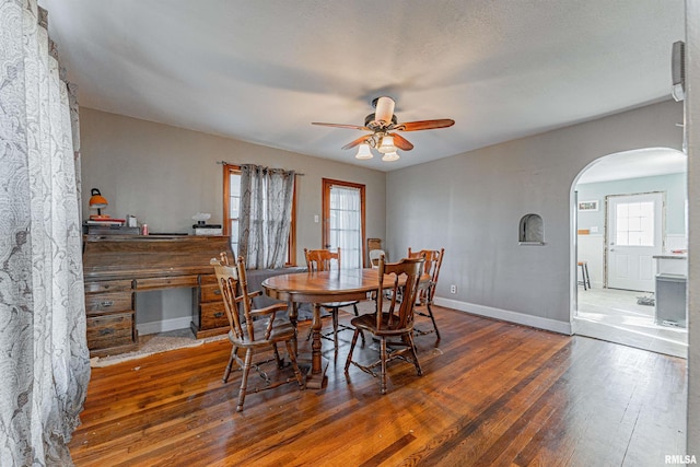 dining space with ceiling fan and dark wood-type flooring