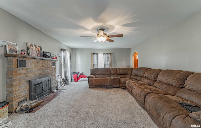 carpeted living room featuring a fireplace and ceiling fan