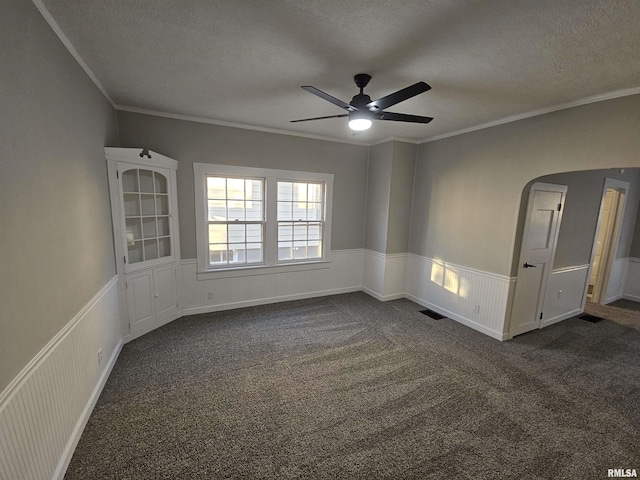 spare room featuring dark colored carpet, a textured ceiling, ceiling fan, and crown molding