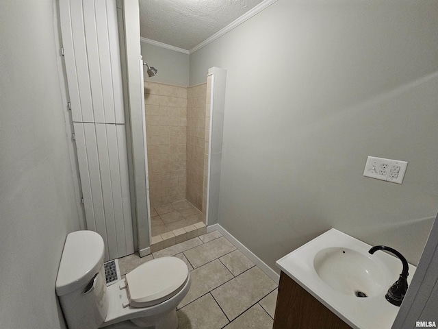 bathroom with vanity, tile patterned flooring, toilet, tiled shower, and a textured ceiling