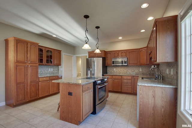 kitchen featuring a center island, sink, hanging light fixtures, appliances with stainless steel finishes, and light stone counters