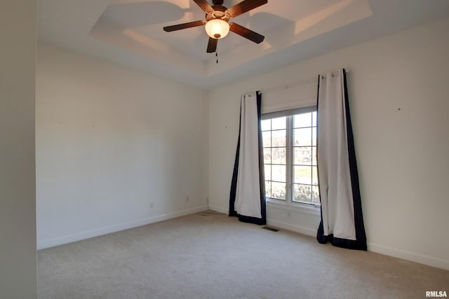 carpeted empty room with a tray ceiling and ceiling fan