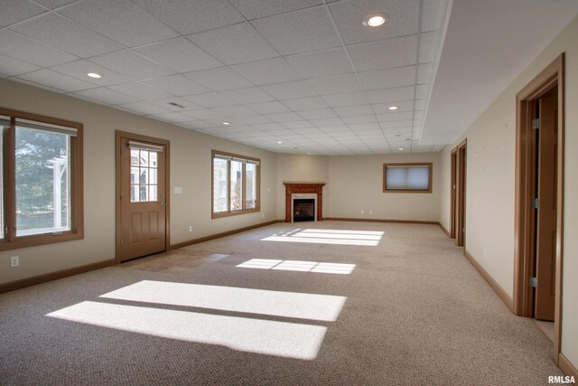 unfurnished living room with light colored carpet and a drop ceiling