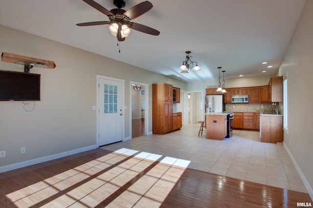 kitchen featuring backsplash, stainless steel appliances, pendant lighting, a kitchen island, and a breakfast bar area