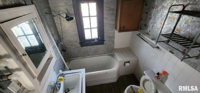 bathroom featuring toilet, tiled shower / bath, and a wealth of natural light