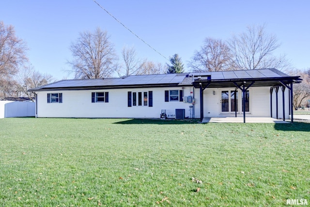 back of property featuring central AC, a patio, a lawn, and solar panels