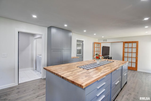 kitchen featuring a kitchen island, wooden counters, gray cabinetry, and light hardwood / wood-style floors