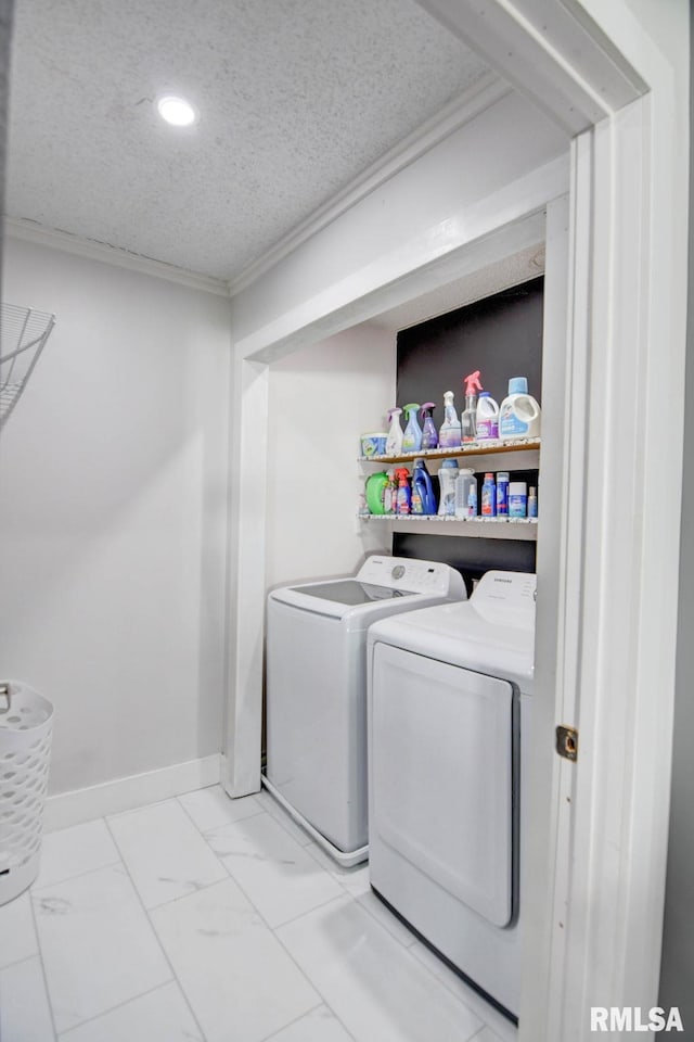 laundry room featuring a textured ceiling, ornamental molding, and washing machine and clothes dryer