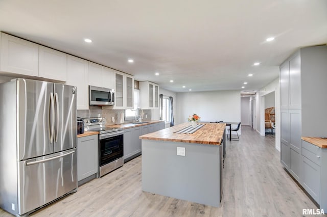 kitchen with sink, wooden counters, light hardwood / wood-style floors, stainless steel appliances, and white cabinets