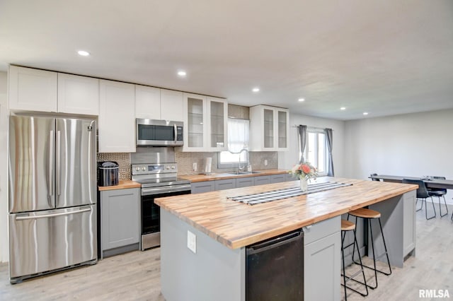 kitchen with white cabinetry, sink, stainless steel appliances, and wood counters