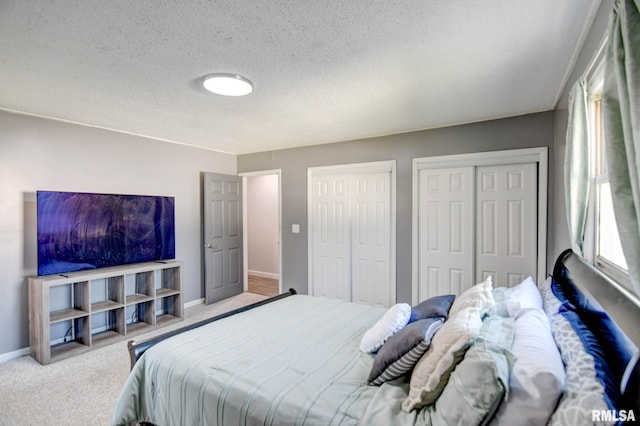 carpeted bedroom featuring a textured ceiling and two closets