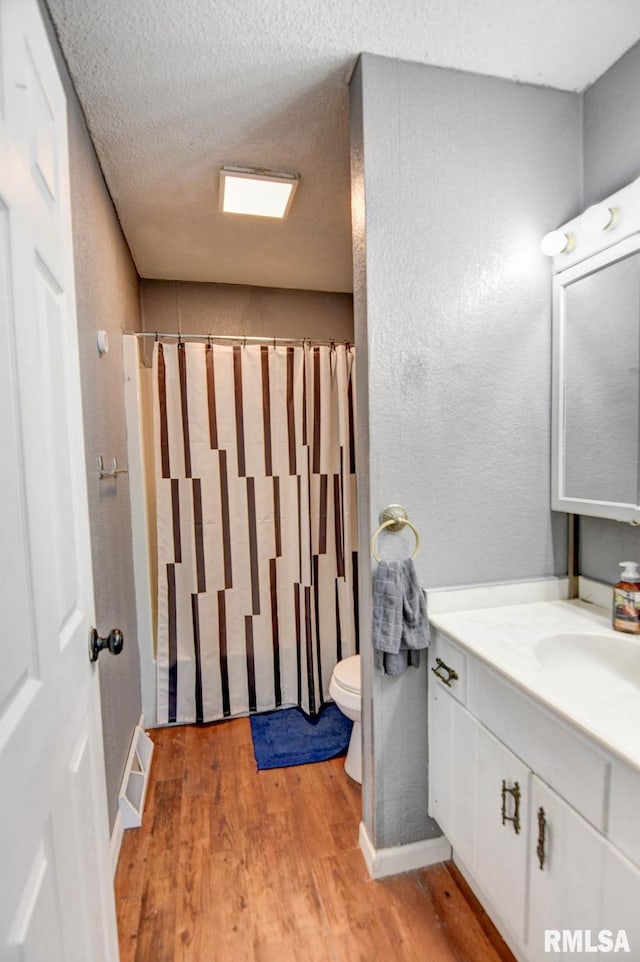 bathroom with toilet, hardwood / wood-style flooring, vanity, and a textured ceiling