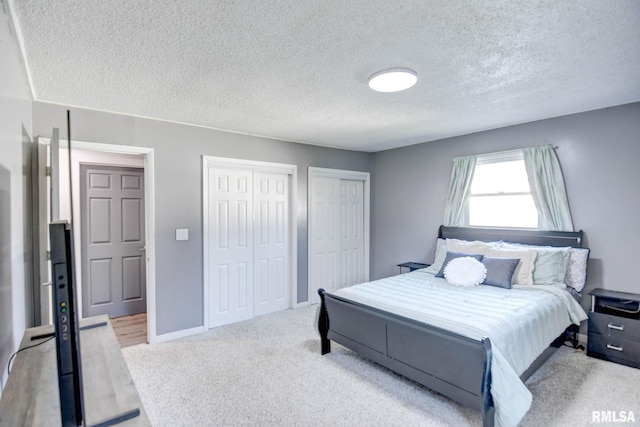 carpeted bedroom with a textured ceiling and two closets