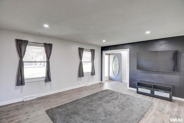 unfurnished living room featuring wood-type flooring and a textured ceiling