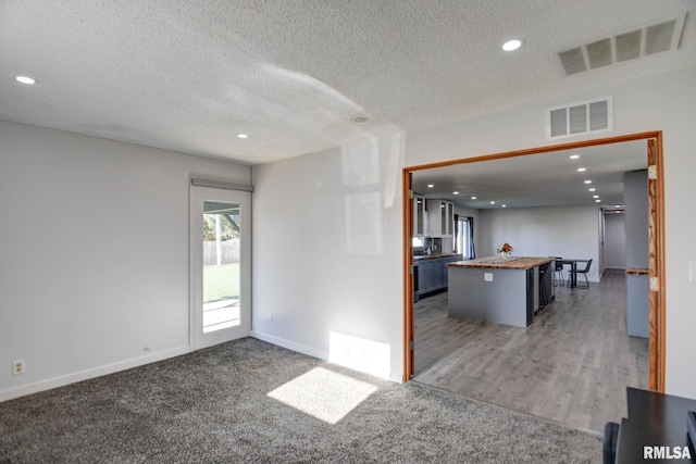 kitchen featuring a center island, dark hardwood / wood-style flooring, wood counters, a textured ceiling, and a breakfast bar area