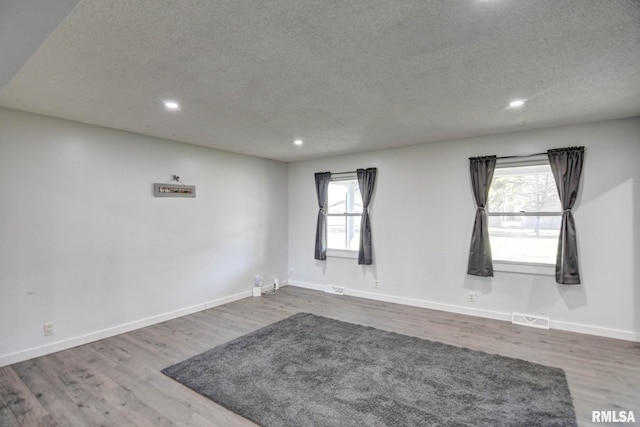 spare room featuring a textured ceiling, hardwood / wood-style floors, and a wealth of natural light