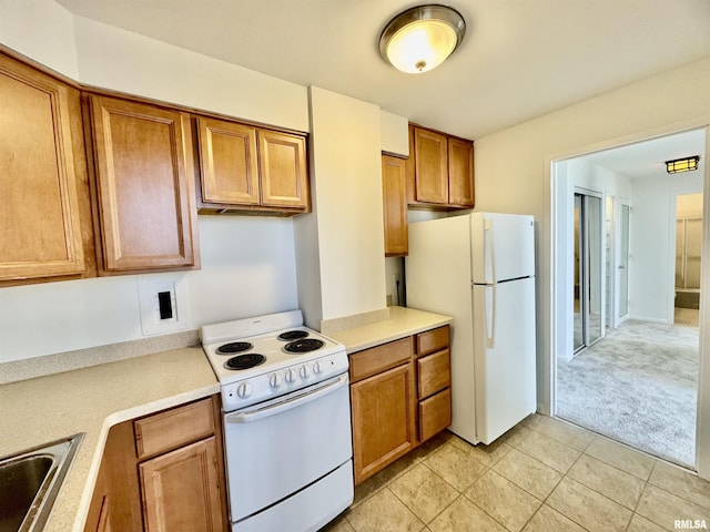 kitchen with sink, white appliances, and light carpet