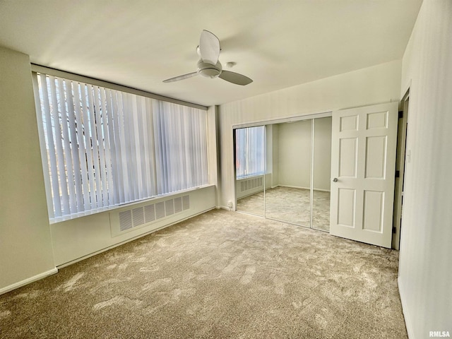 unfurnished bedroom featuring ceiling fan, light colored carpet, and a closet