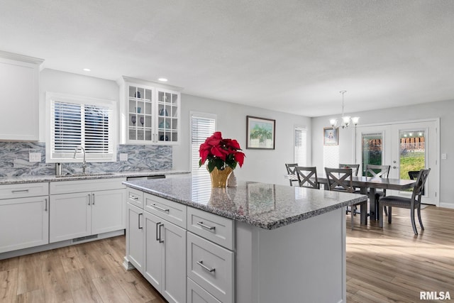 kitchen with white cabinets, a center island, sink, and light hardwood / wood-style flooring