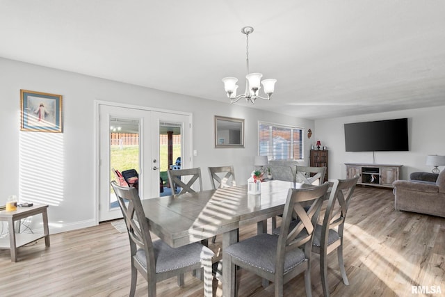 dining space with french doors, light hardwood / wood-style floors, and a notable chandelier