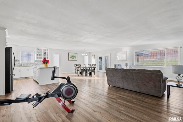 living room featuring a chandelier, a textured ceiling, light wood-type flooring, and sink