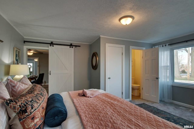 bedroom featuring carpet, a barn door, ornamental molding, a textured ceiling, and connected bathroom