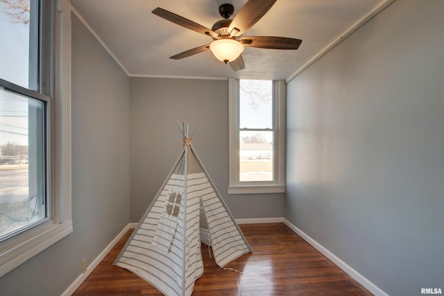 playroom featuring ceiling fan, dark hardwood / wood-style flooring, and crown molding