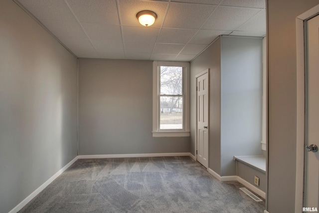 carpeted empty room featuring a paneled ceiling