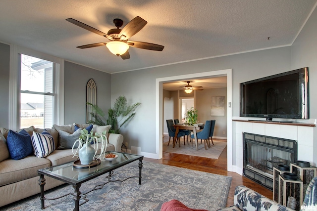 living room with crown molding, a fireplace, wood-type flooring, and a textured ceiling