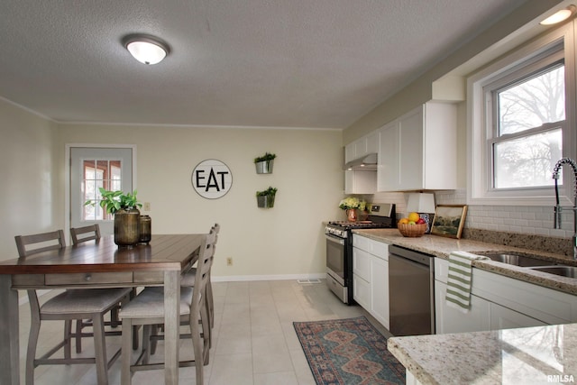 kitchen featuring backsplash, a textured ceiling, stainless steel appliances, sink, and white cabinetry