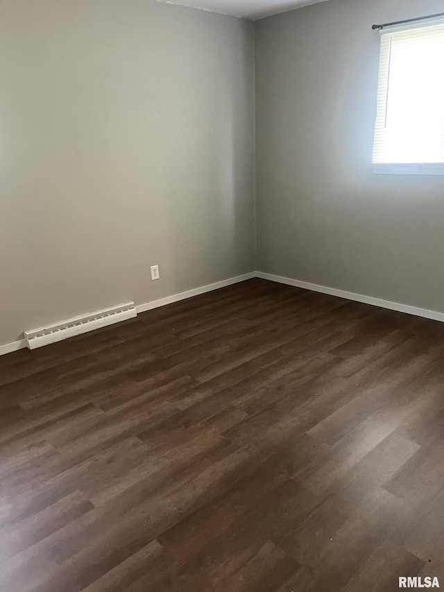 empty room with a baseboard radiator and dark hardwood / wood-style flooring