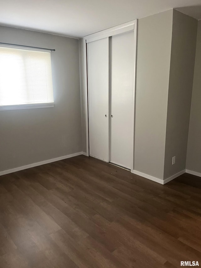 unfurnished bedroom with a closet and dark hardwood / wood-style floors