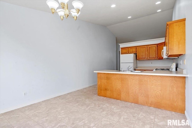 kitchen with kitchen peninsula, white appliances, vaulted ceiling, and sink