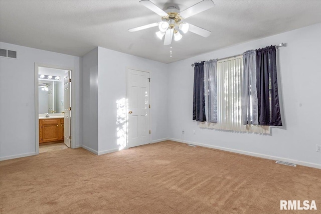 unfurnished bedroom with ceiling fan, light colored carpet, and connected bathroom